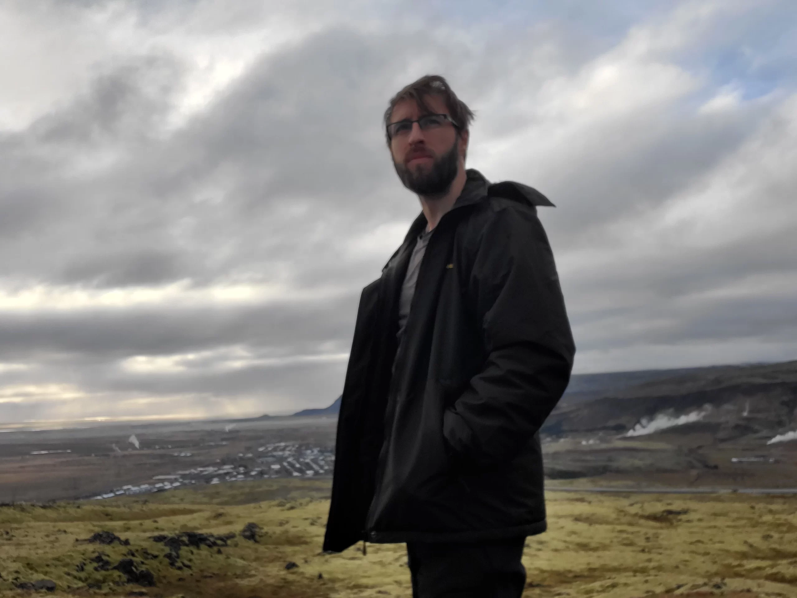 Exploring the world standing atop a hill overlooking the town and landscape of Iceland.